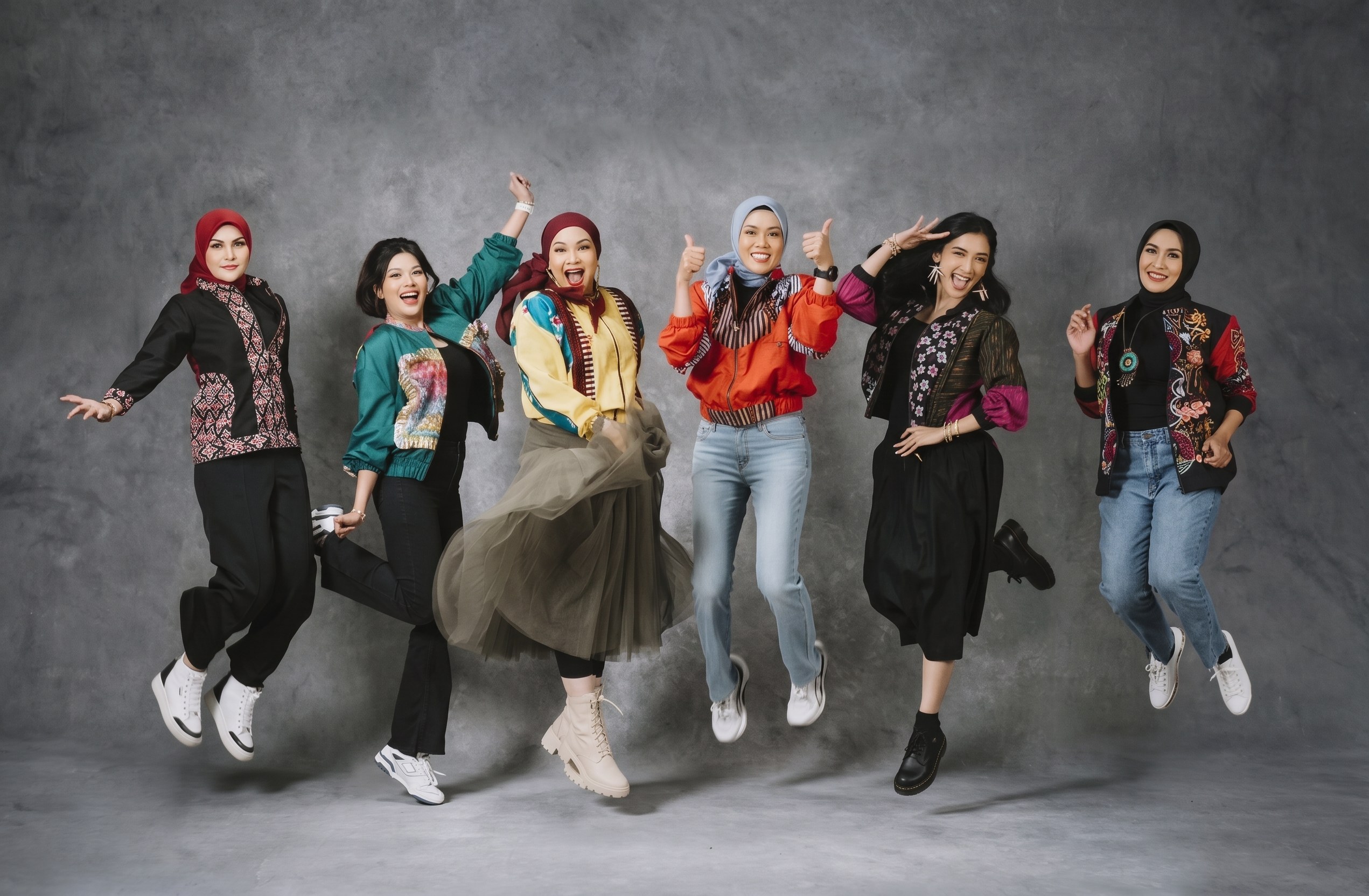 Enam pemakai Cutenik melompat bersama, mengenakan outer bermotif tenun, batik, dan lurik